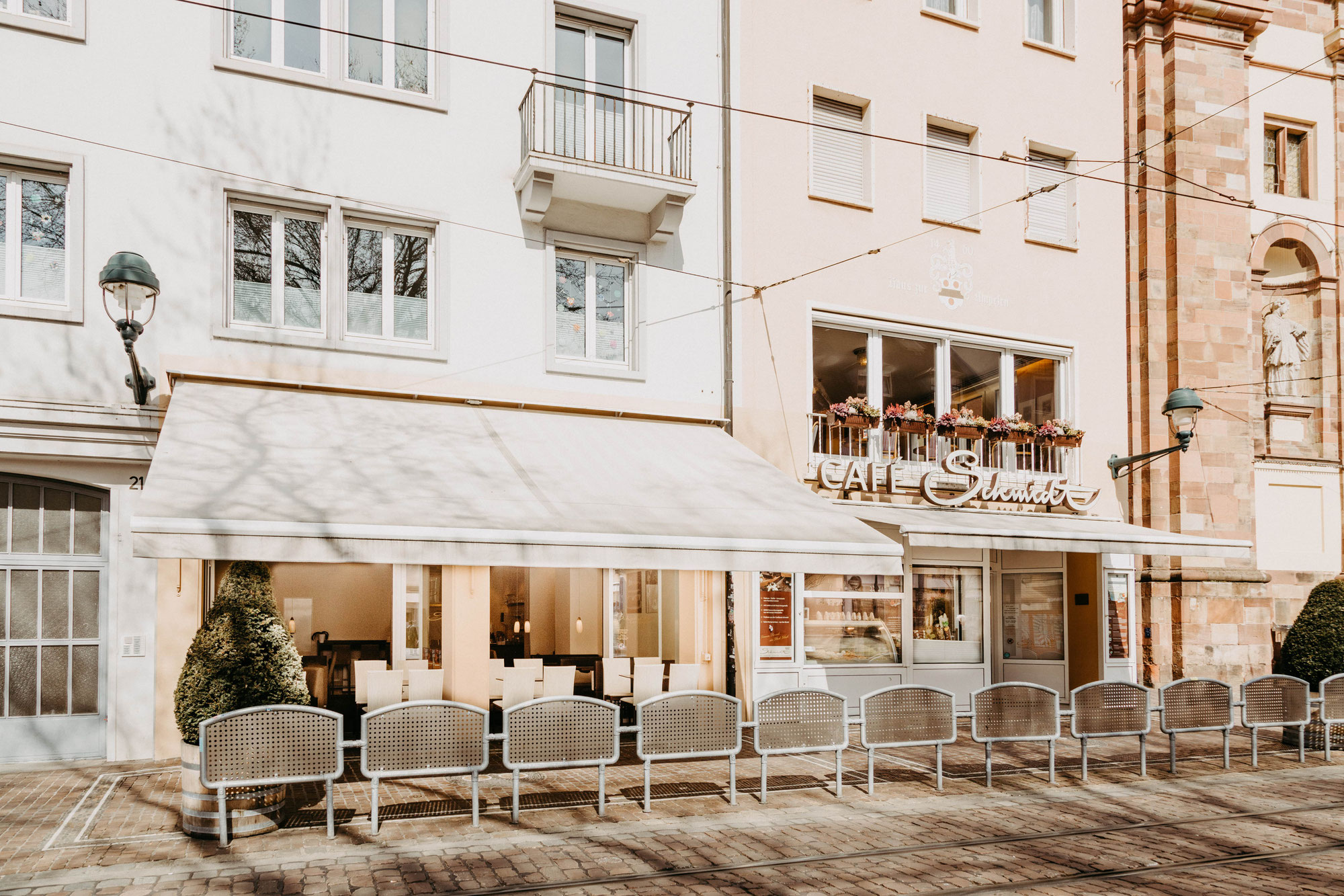 Außenansicht von Café Schmidt in der Freiburger Altstadt mit Terrasse und Markise